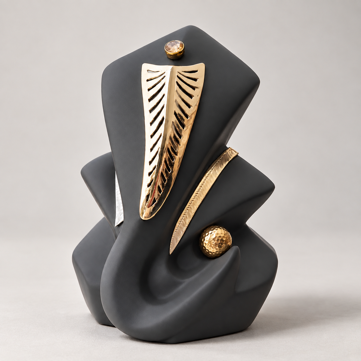 Abstract grey sculpture of Ganesha with textured silver embellishment on his trunk; a round shaped goldplated motif, and a zircon stone on forehead.