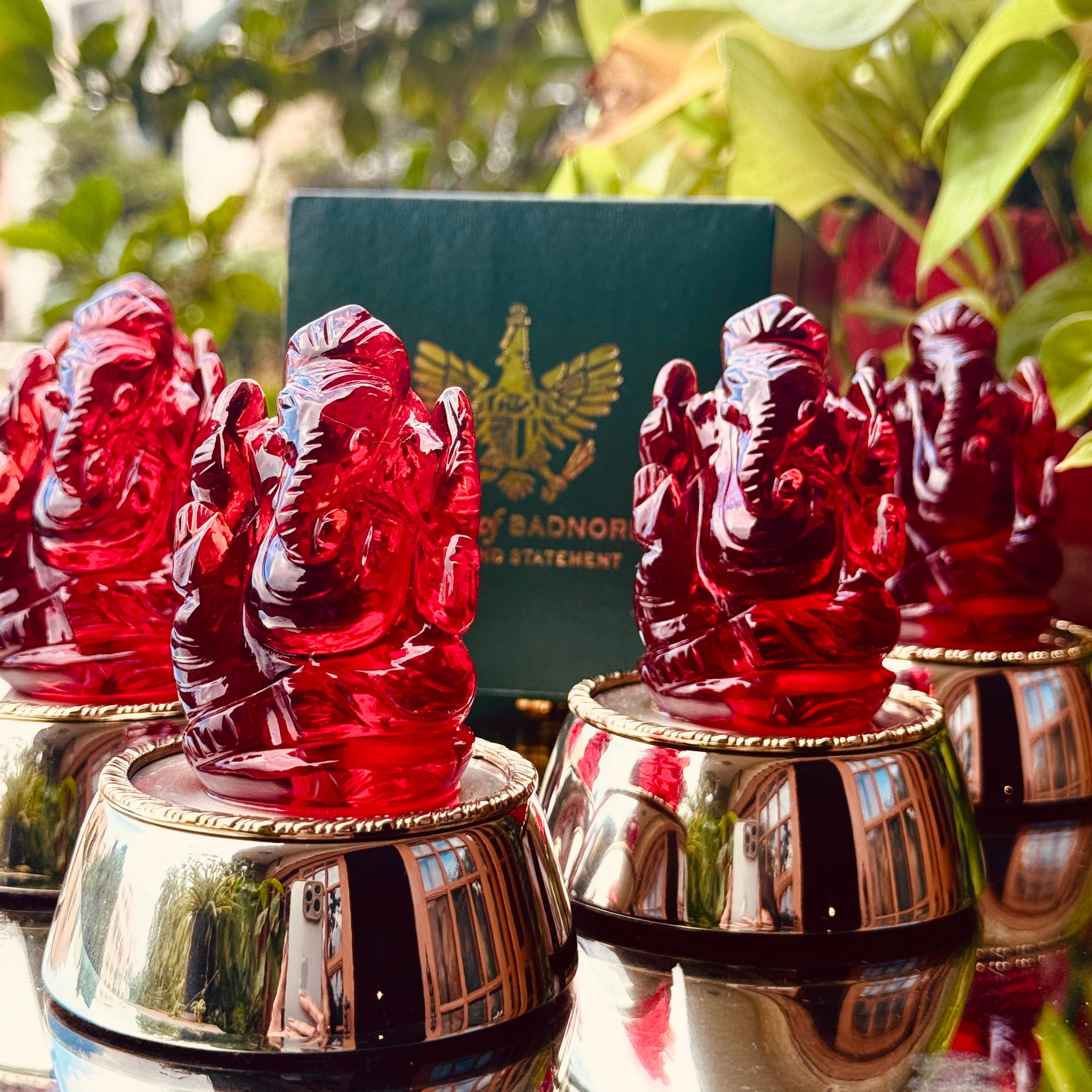 Red Ganesh statues on metallic bases with a blurred background